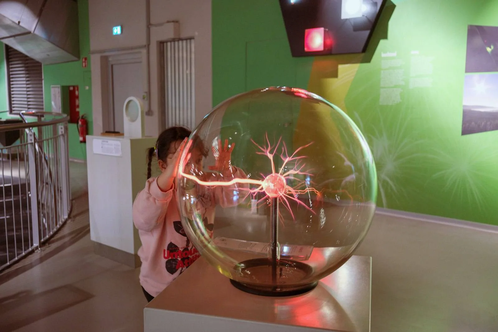 Anak menyentuh bola plasma di pameran sains